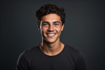 Fototapeta premium Portrait of a grinning man in his 20s smiling at the camera over blank studio backdrop