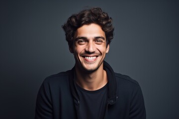 Obraz premium Portrait of a grinning man in his 20s smiling at the camera on blank studio backdrop