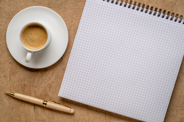 blank spiral notebook with grid paper, flat lay with coffee on textured art paper