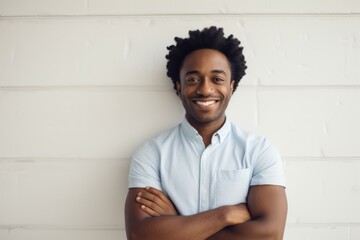Portrait of a joyful afro-american man in his 30s with arms crossed over light wood minimalistic setup