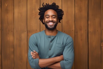 Portrait of a joyful afro-american man in his 30s with arms crossed isolated in light wood minimalistic setup