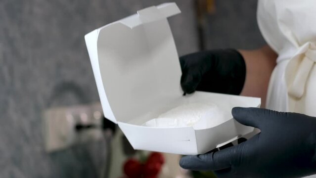 female hands in black gloves pack cheese Food concept French organic goat cheese Picodon form southern France on wooden board with copy space