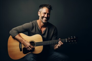 Portrait of a grinning man in his 40s playing the guitar isolated on light wood minimalistic setup