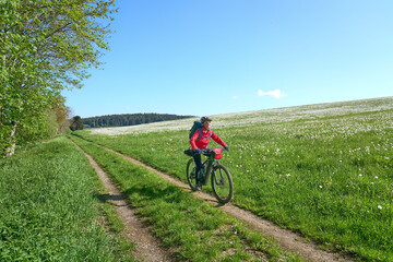 Naklejka premium active senior woman on a bike packing tour with her electric mountain bike in the Bavarian Forest near Waldkirchen, Bavaria, Germany 