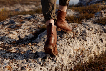 Adventure boots resting on rocky hill overlooking water in travel destination