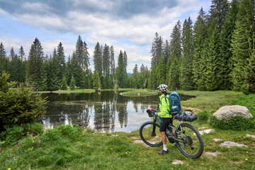 active senior woman on a bike packing tour with her electric mountain bike in the Bavarian Forest...