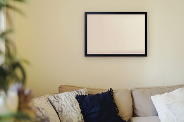 A white frame with a blank canvas against a light wall and on a wooden tabletop with vase. Layout concept for photography, poster or painting. Copy space.