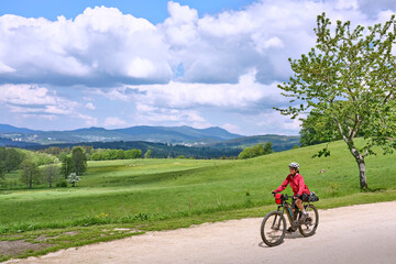 Obraz premium active senior woman on a bike packing tour with her electric mountain bike in the Bavarian Forest near Waldkirchen, Bavaria, Germany