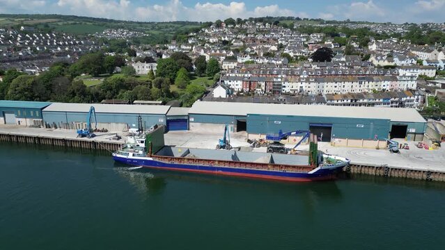 Teignmouth, South Devon, England: DRONE VIEWS: A cargo ship is loaded with ball clay by dockside loaders. The port of Teignmouth also receives imports of animal feed, aggregate and salt (Clip 10).