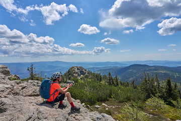 Fototapeta premium active senior woman on a bike packing tour with her electric mountain bike in the rocky the summit of Great Arber in the Bavarian Forest, Bavaria, Germany