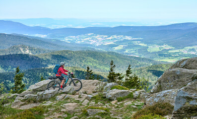 Fototapeta na wymiar active senior woman on a bike packing tour with her electric mountain bike in the rocky the summit of Great Arber in the Bavarian Forest, Bavaria, Germany