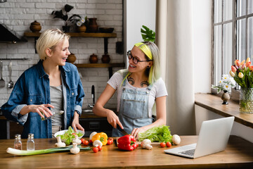 Happy caucasian lesbian lgbtq couple having fun while cooking preparing food salad romantic dinner...