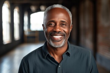 Obraz premium Portrait of a joyful afro-american man in his 50s smiling at the camera isolated on empty modern loft background