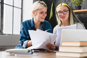 Paperwork, documents, bills and payments. Caucasian young coworkers female lesbian couple working together, dealing with financial papers cheques at home office