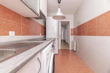 Kitchen with combined white and light brown tiles, stainless steel sink, white refrigerator, white...