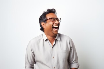Obraz premium Portrait of a joyful indian man in his 40s laughing in front of plain white digital canvas