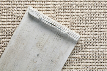 Fragment of empty white wooden tray on table covered with beige knitted plaid. Template for...