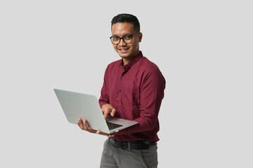 A young handsome Asian man in a suit wearing glasses and making various facial expressions and holding a laptop.