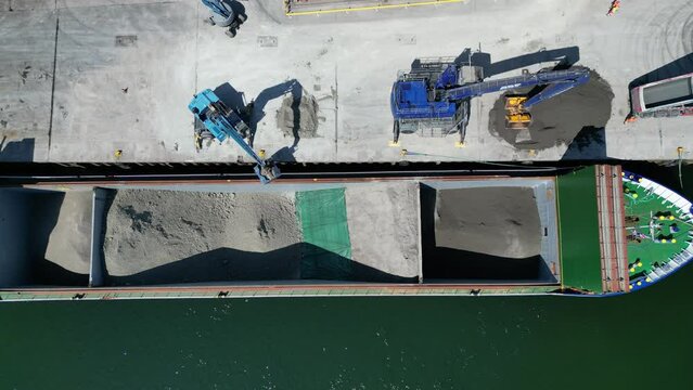 Teignmouth, South Devon, England: DRONE VIEWS: A cargo ship is loaded with ball clay by dockside loaders. The port of Teignmouth also receives imports of animal feed, aggregate and salt (Clip 1).