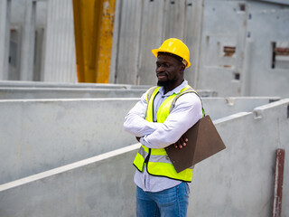 Portrait of handsome African foreman looking into camera wearing reflective bib and yellow hard...
