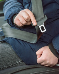 A 10-12 year old child fastens a seat belt in a car. Vertical view