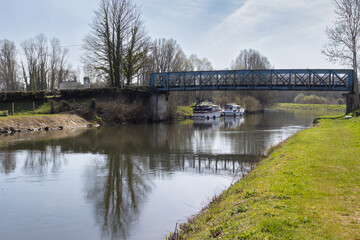 Obraz premium Spring view of Eaucourt-sur-Somme bridge near Abbeville, and the River Somme as it flows through the commune of Eaucourt-sur-Somme in the Somme department of Hauts-de-France in northern France.