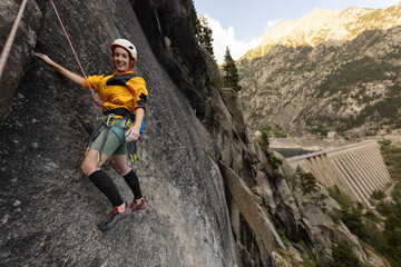 A woman is climbing a rock wall with a smile on her face