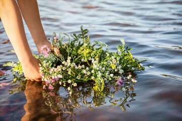 Flower Wreath on Water River. Girl's Hands Put Wreath on River Water in Sunset. Slavic Symbol of...