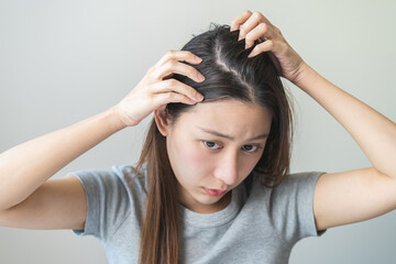 Damaged Hair symptom, face serious asian young woman, girl worry about balding, looking at scalp in...