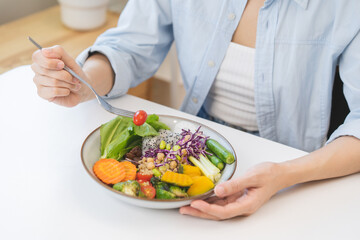 Diet concept, close up young woman hand use fork to prick tomato, fresh vegetable, green salad in plate, eat nutrition food on plate at home, low fat to good body. Girl getting weight loss for healthy