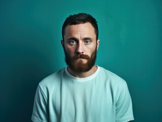 Turquoise background sad european white man realistic person portrait of young beautiful bad mood 
