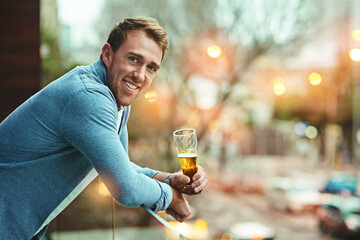 Man, portrait and beer on balcony with smile for relax, celebrate in city for wellness. Male...