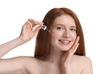 Smiling woman with freckles applying cosmetic serum onto her face against white background