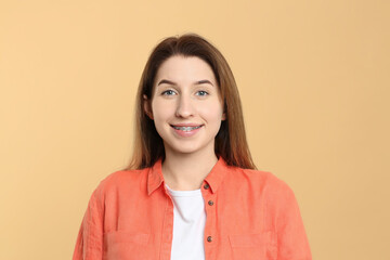 Portrait of smiling woman with dental braces on beige background