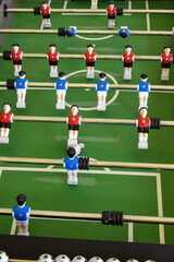 Classic Foosball Table Game With Players in Red and Blue Jerseys During Daytime Indoor Match. Close-up view of foosball table featuring red and blue jersey players positioned for daytime indoor game.