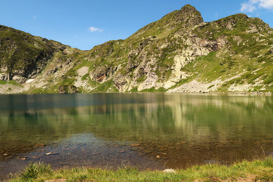 The mountains are reflecting on green, blue and turquoise water of the Kidney, Babreka Lake, one of the Seven Rila Lakes, situated on a plateau in the Rila National Park, close to Sofia, Bulgaria