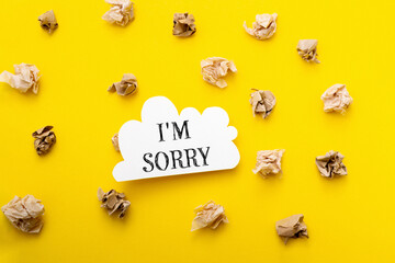 A yellow background with a white sign that says I'm sorry on it