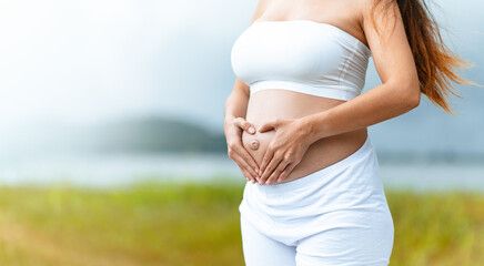 mother, pregnancy, motherhood, anticipation, child, pregnant, birth, human, stomach, health. A woman is holding her stomach possibly to show her pregnancy, with the woman standing in a grassy field.
