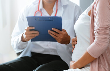 motherhood, health care, expecting, pregnant, childbirth, document, exam, examining, healthcare, patient. A doctor is talking to a pregnant woman. The doctor is holding a clipboard.