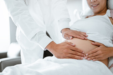 doctor, health, healthcare, hospital, human, massage, illness, nurse, occupation, patient. A woman is laying on a bed with a doctor touching her stomach.