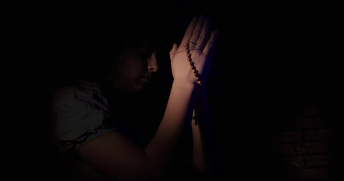 Woman Praying In The Dark With A Rosary