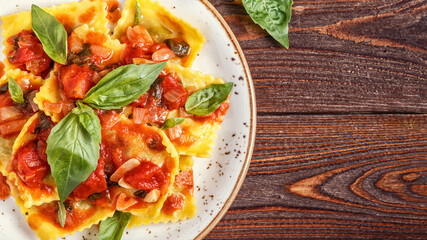 Ravioli with tomato sauce and basil on dark background.