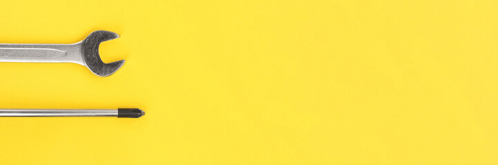 Work tools, wrench and screwdriver on bright yellow background banner. Panoramic web header. Wide...