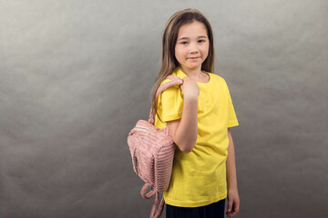 Close-up portrait of an Asian teenage girl wearing a yellow t-shirt on a gray background, copy space