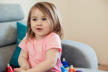 Little funny girl with blue eyes, playing in her room on the couch. Copy space, close up.