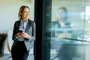 Businesswoman chatting on phone in stylish office building at noon