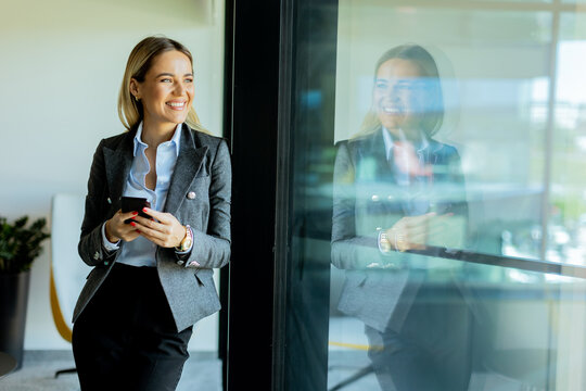 Businesswoman chatting on phone in stylish office building at noon