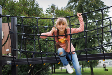 Child, monkey bars and energy on playground, smiling and obstacle course on outdoor adventure at park. Happy girl, active and exercise on jungle gym, fitness on vacation or holiday