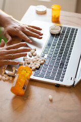 Person with addiction taking pills over his laptop with many pills around, desesperate