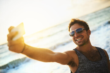 Happy, man and smartphone for selfie with sunglasses outdoor at beach for summer holiday...